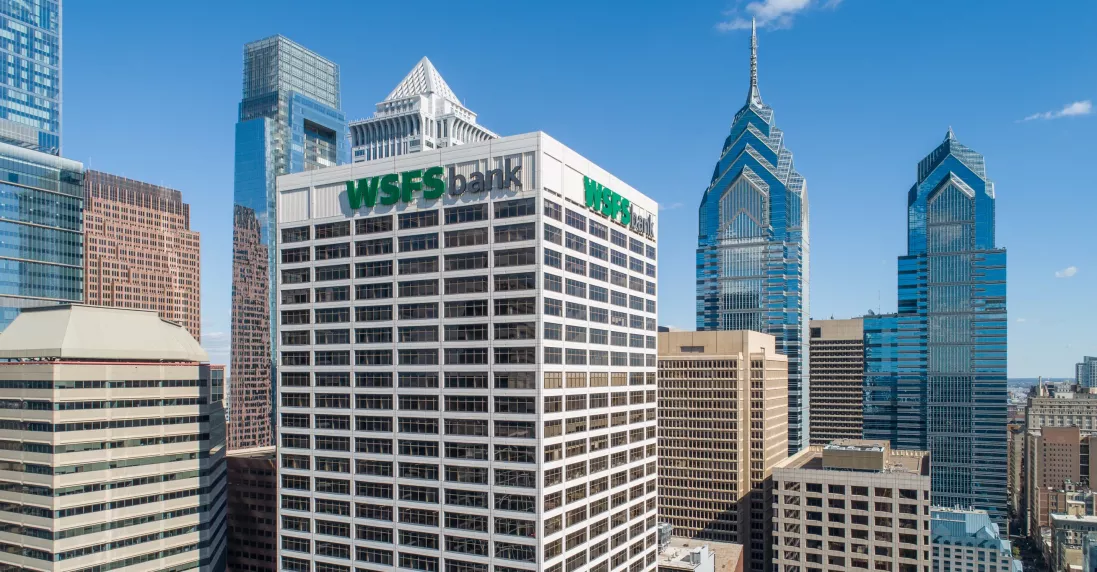 Aerial view of 1818 Market Street, a high-rise commercial office building in downtown Philadelphia with prominent “WSFS Bank” signage, surrounded by modern skyscrapers including the iconic Liberty Place towers, set against a clear blue sky.
