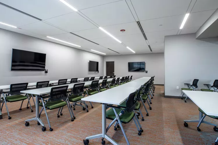 Modern conference or training room at 1818 Market featuring rows of mobile tables and ergonomic chairs, wall-mounted flat screen displays, and contemporary lighting in a clean, professional setting.